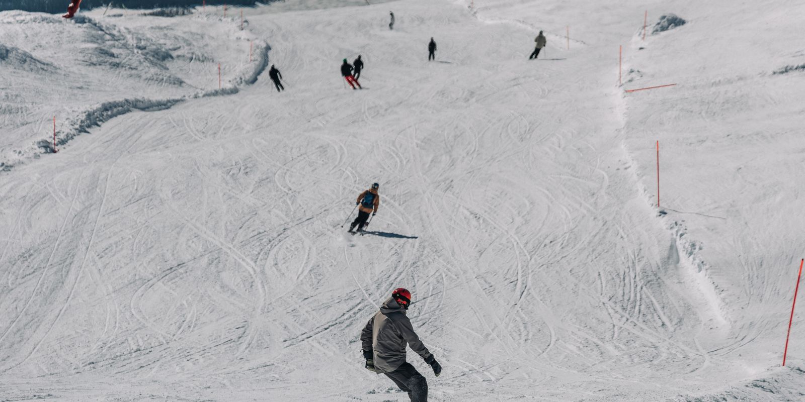 Snowboarders and skiers enjoying a clear day on a snowy mountain slope