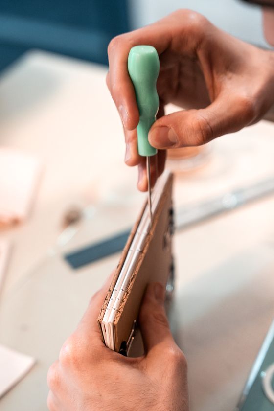 Hands sewing a book signature with thread and awl — photo by Nur Demirbas on Pexels