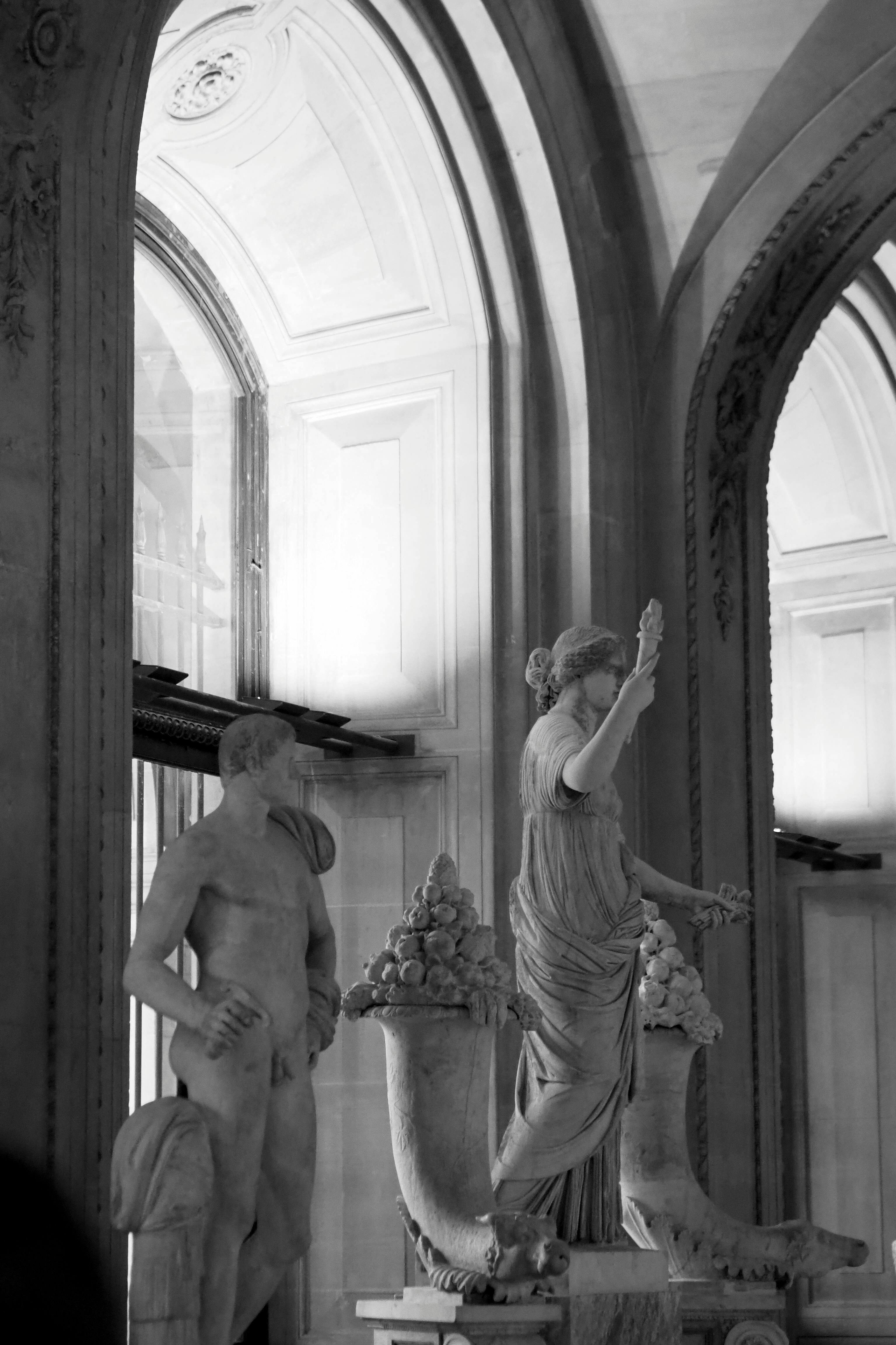 Gratuit Photographie en noir et blanc de statues classiques à l'intérieur du Louvre, capturant des détails complexes. Photos