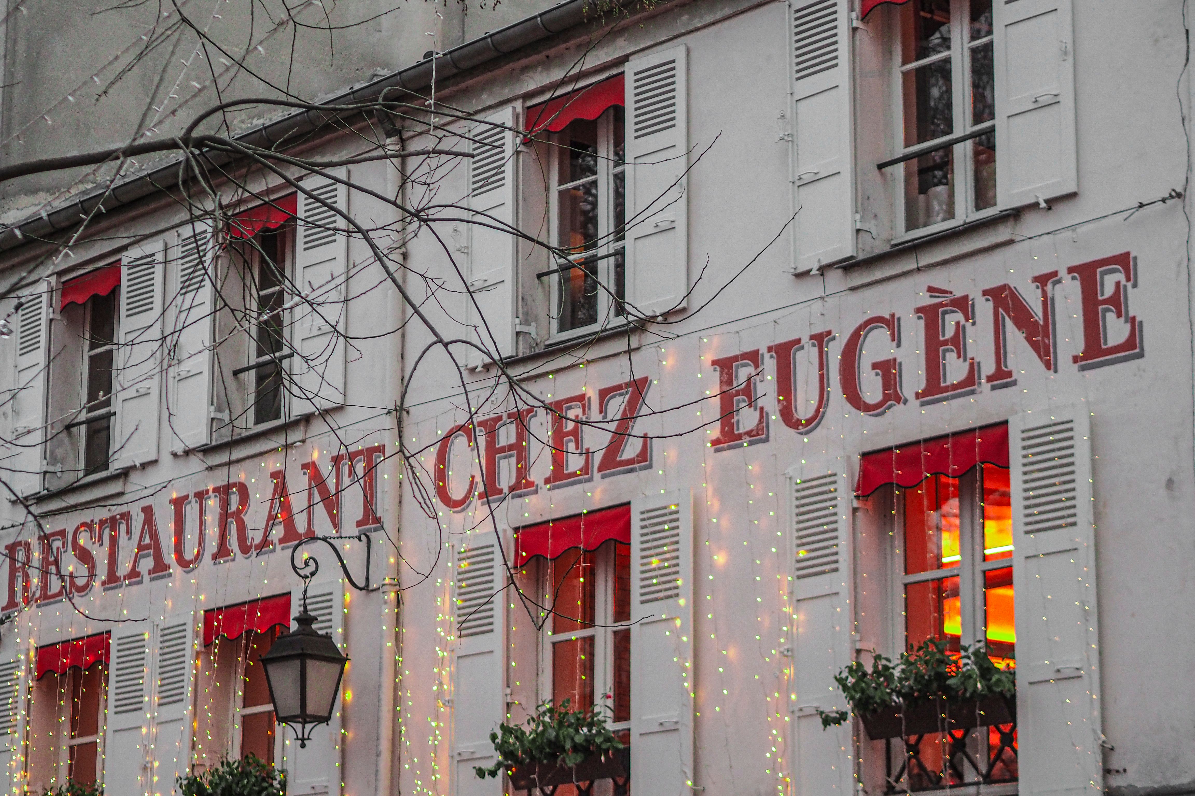 Street view of Restaurant Chez Eugène in Montmartre, Paris with twinkling lights.