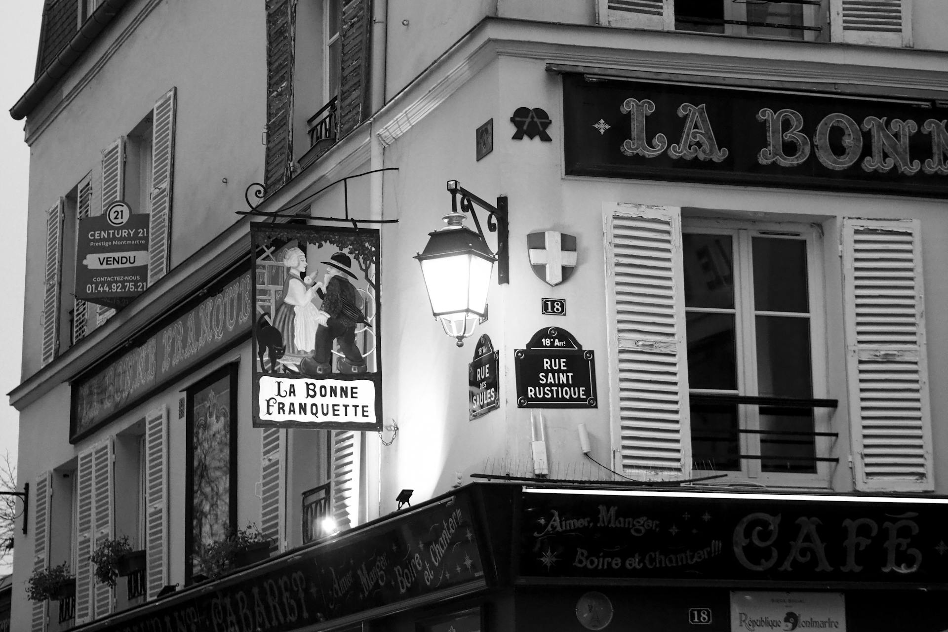 Black and white image of a Montmartre café in Paris, exuding classic French charm.