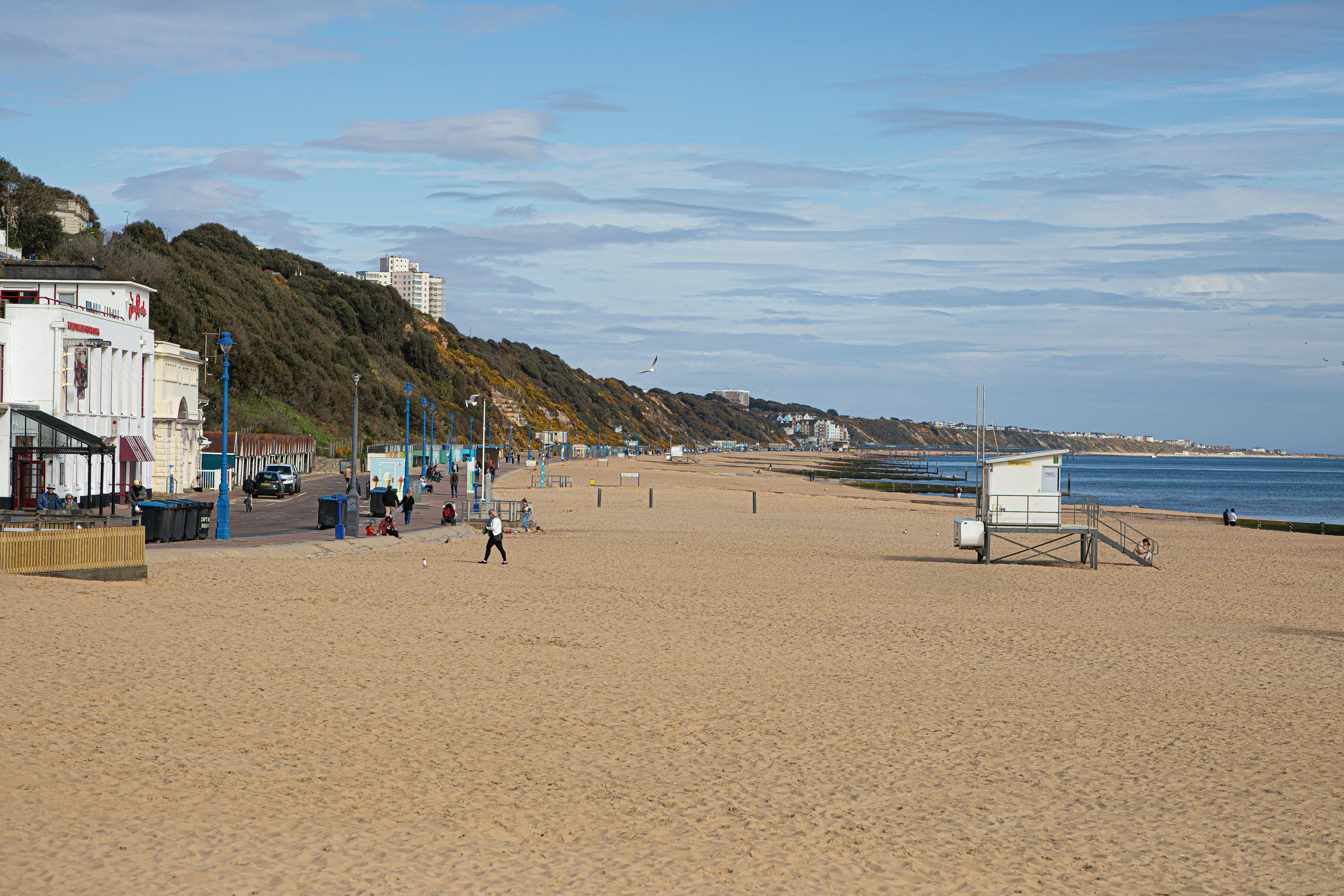 Explore the sandy beach and distant promenade of Bournemouth, England on a sunny day.