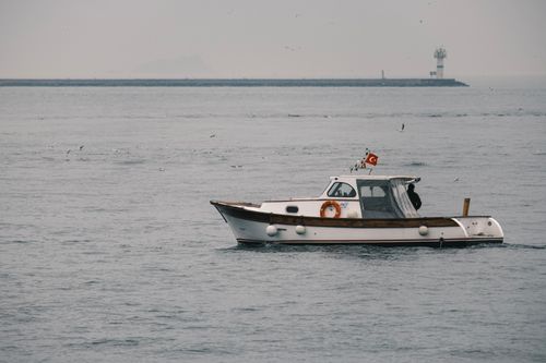 Free A serene view of a boat on the sea near İstanbul with a lighthouse in the background. Stock Photo