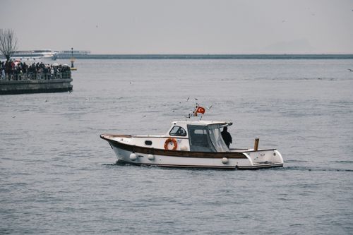 Free A small boat sails on the Bosphorus with a view of İstanbul and a crowd nearby. Stock Photo