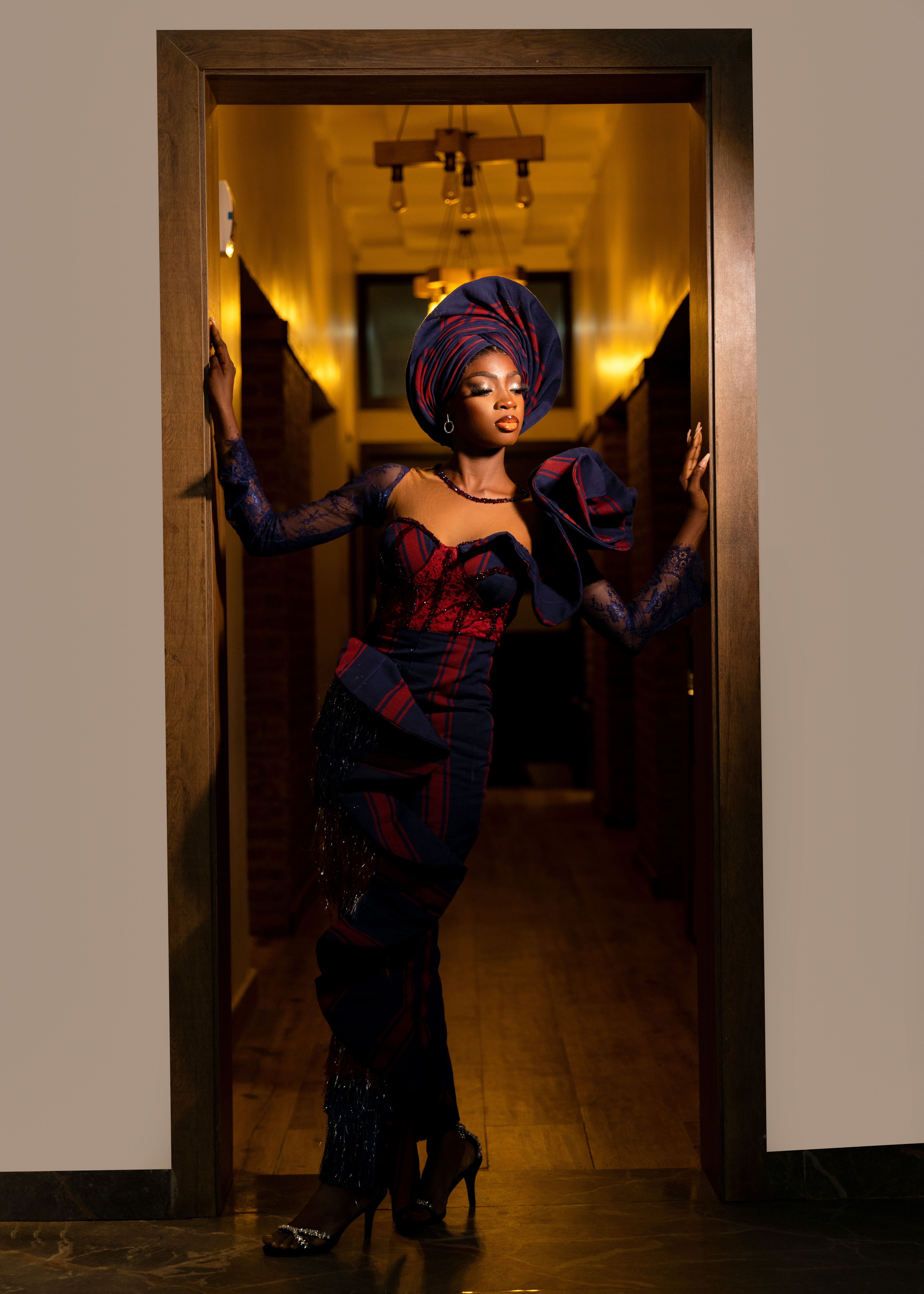Confident woman in traditional attire posing indoors with dramatic lighting for cultural fashion photo.