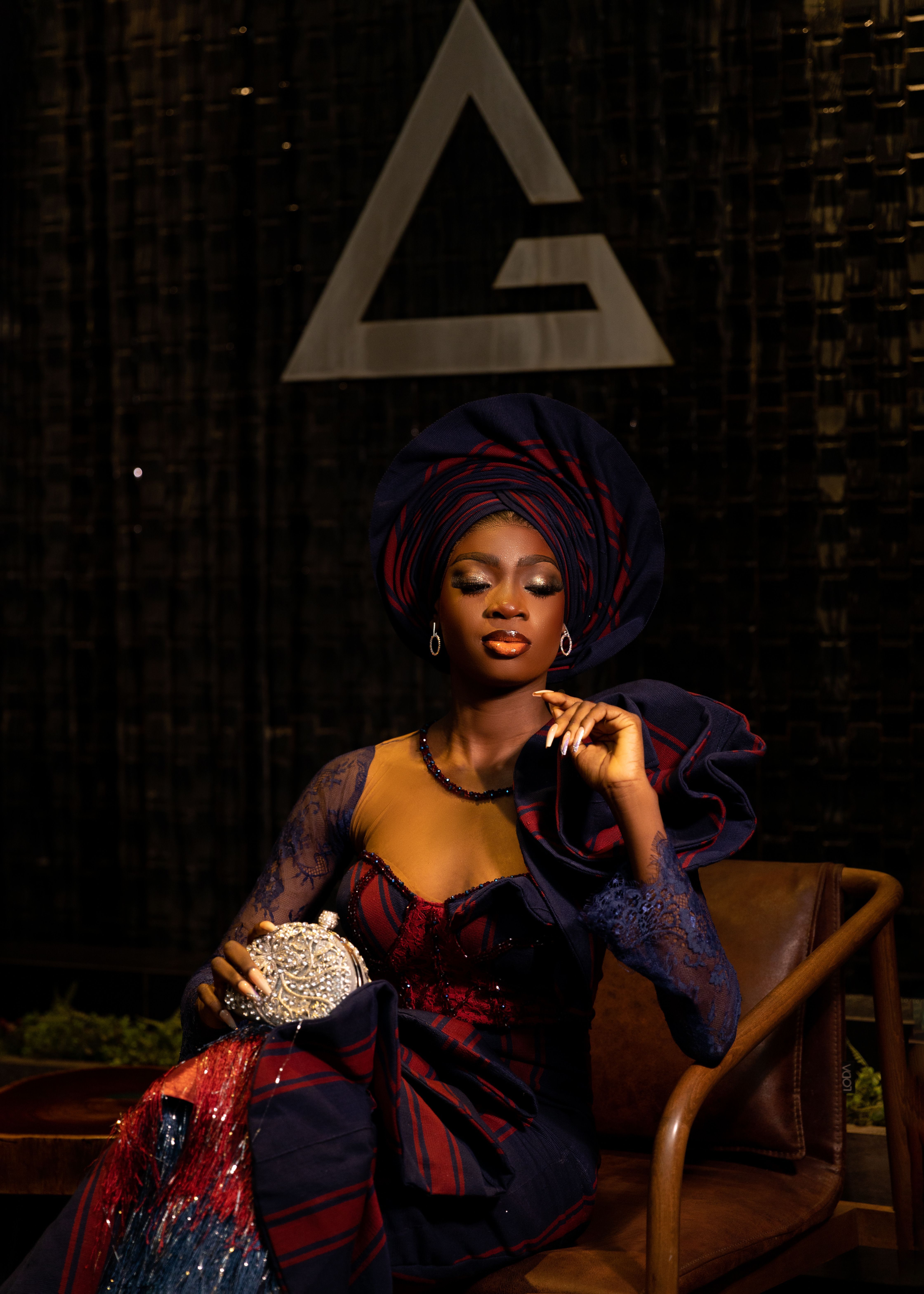 Confident woman in vibrant evening attire with a stylish headwrap, exudes elegance and sophistication.