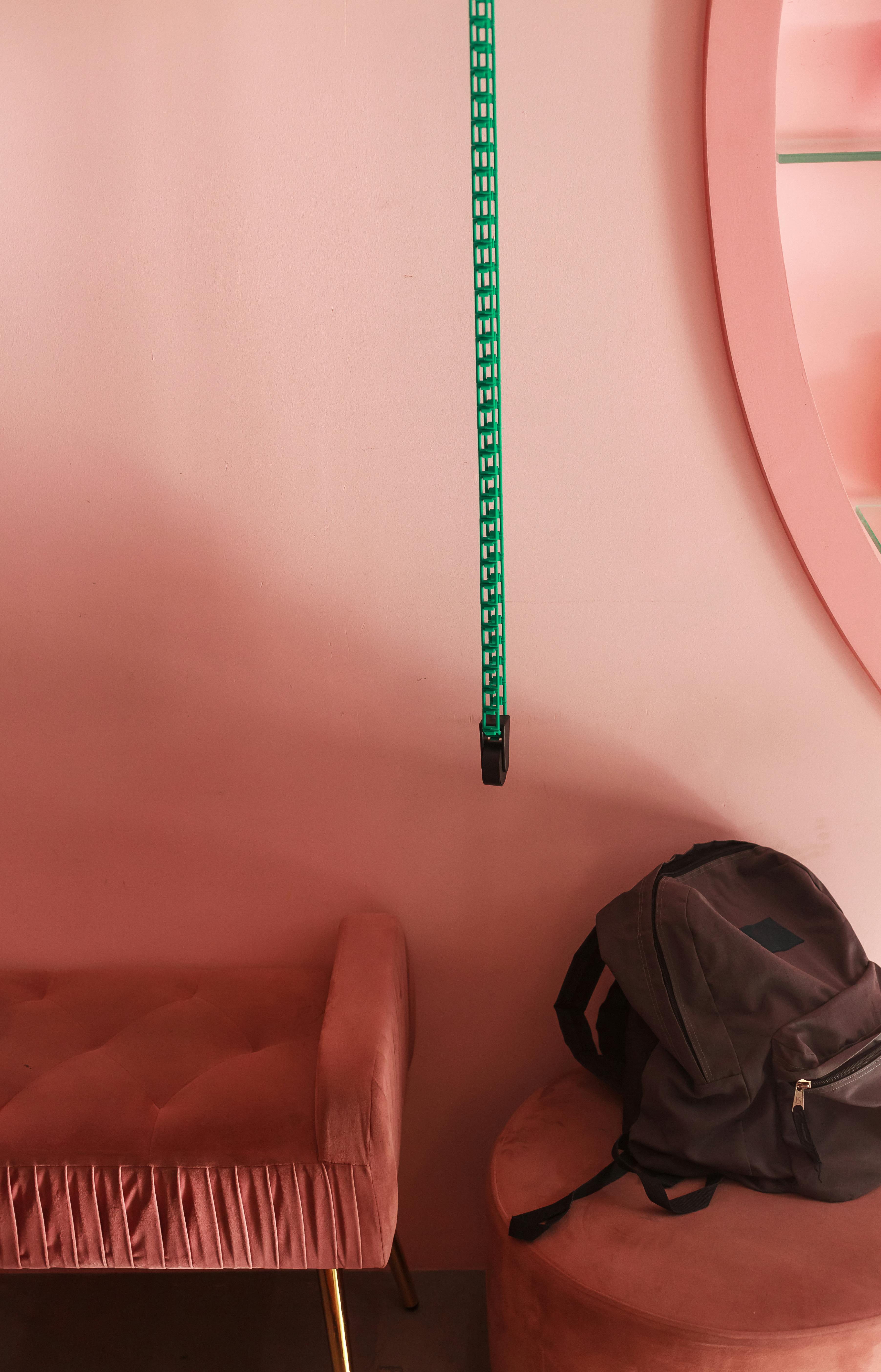 Gratis Interior elegante con muebles de color rosa con una mochila gris y una correa verde que contrasta colgando. Foto de stock