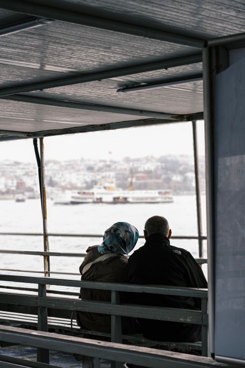 Free Couple sitting on ferry overlooking cityscape on a tranquil day. Stock Photo