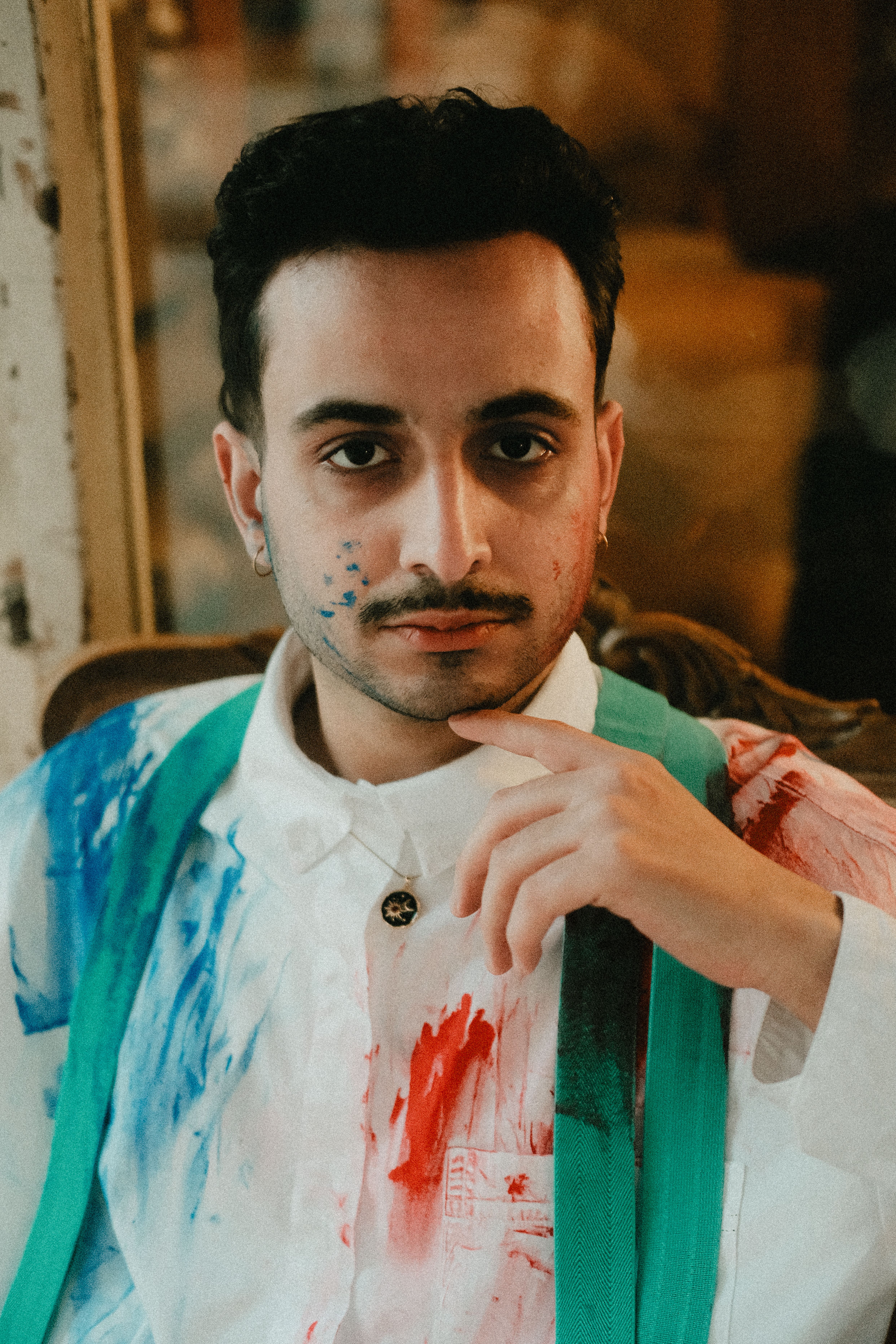 Portrait of a young man with colorful paint on his face in İstanbul, exuding confidence.