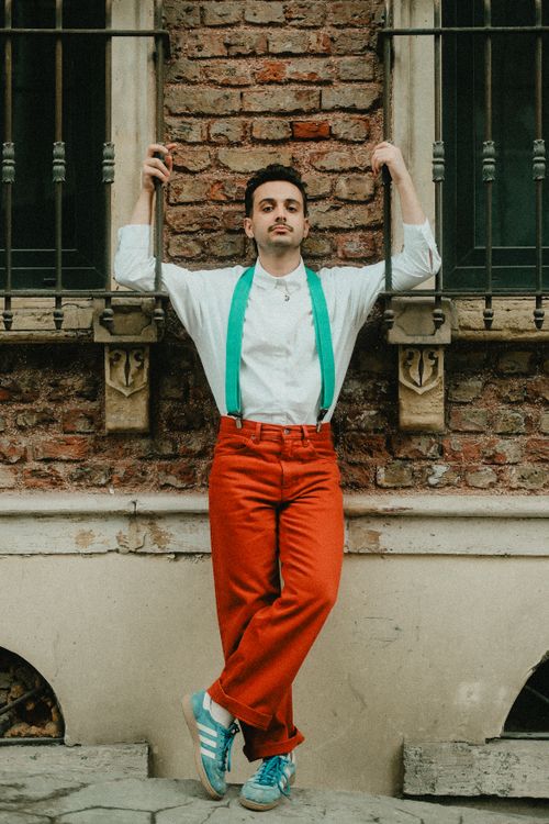 Free Stylish young man in vibrant attire leaning against a historic brick wall in Istanbul. Stock Photo