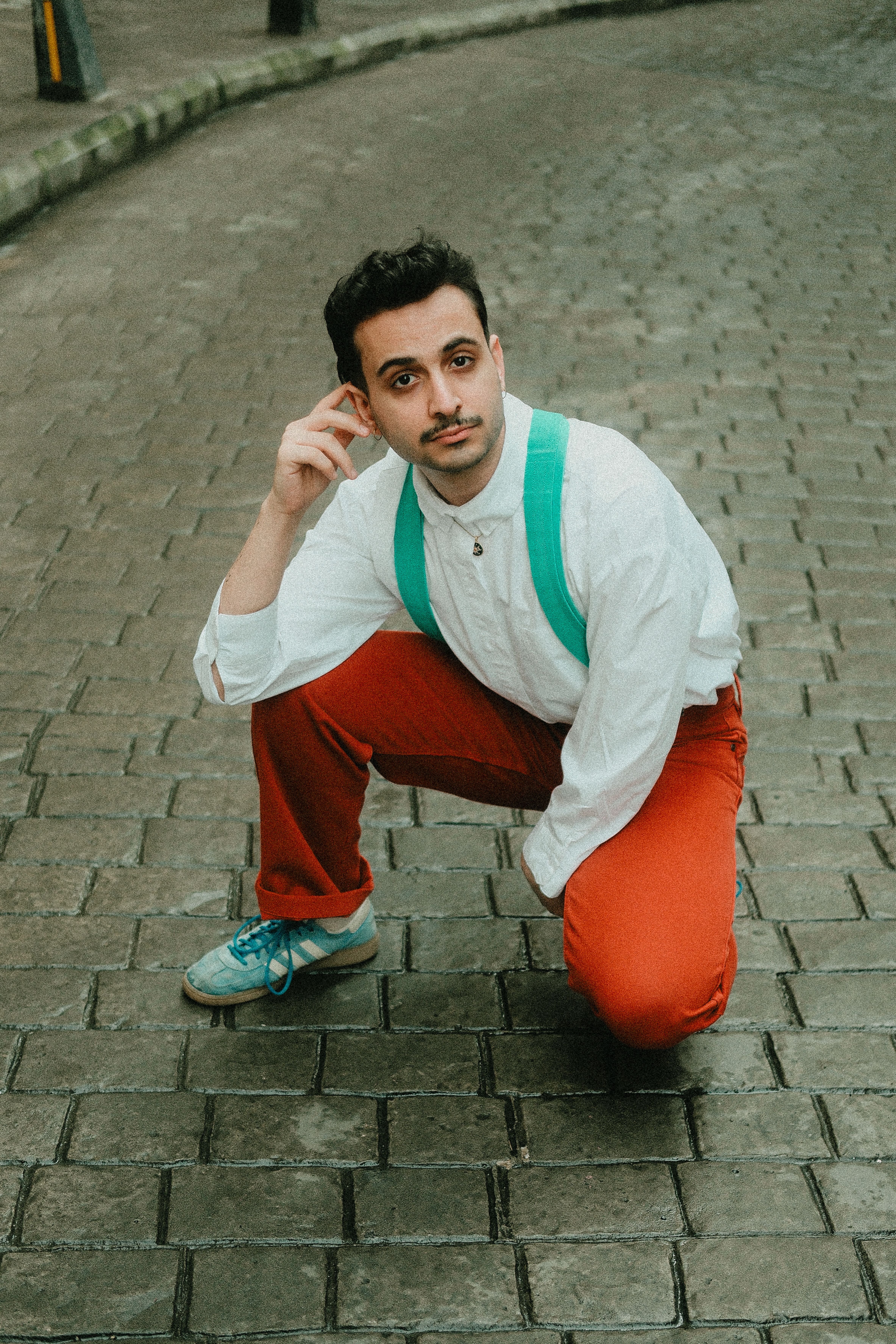 Young man posing on cobblestone street outdoors
