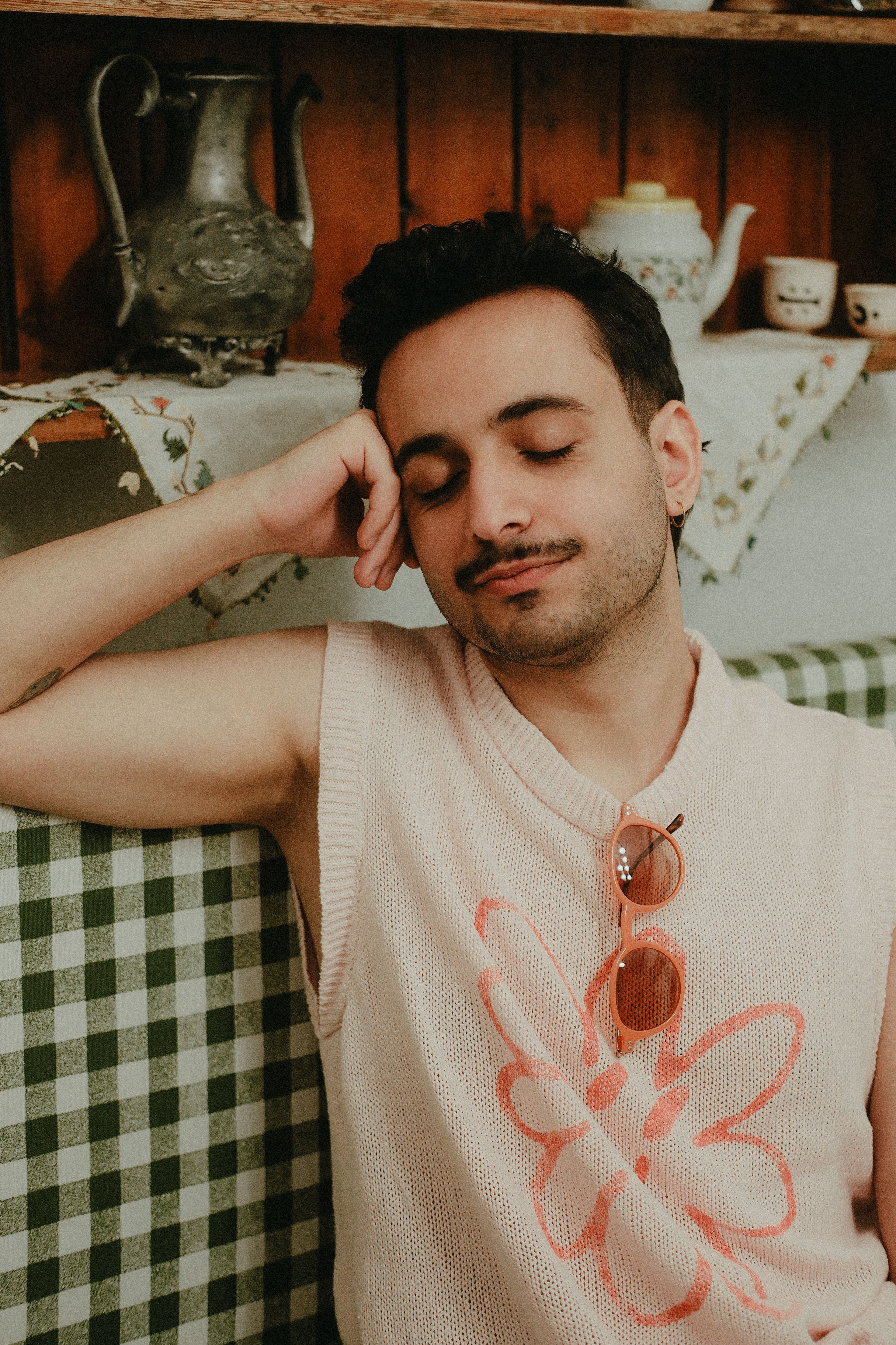 Calm young man enjoying a moment of relaxation indoors with vintage decor and subtle colors.