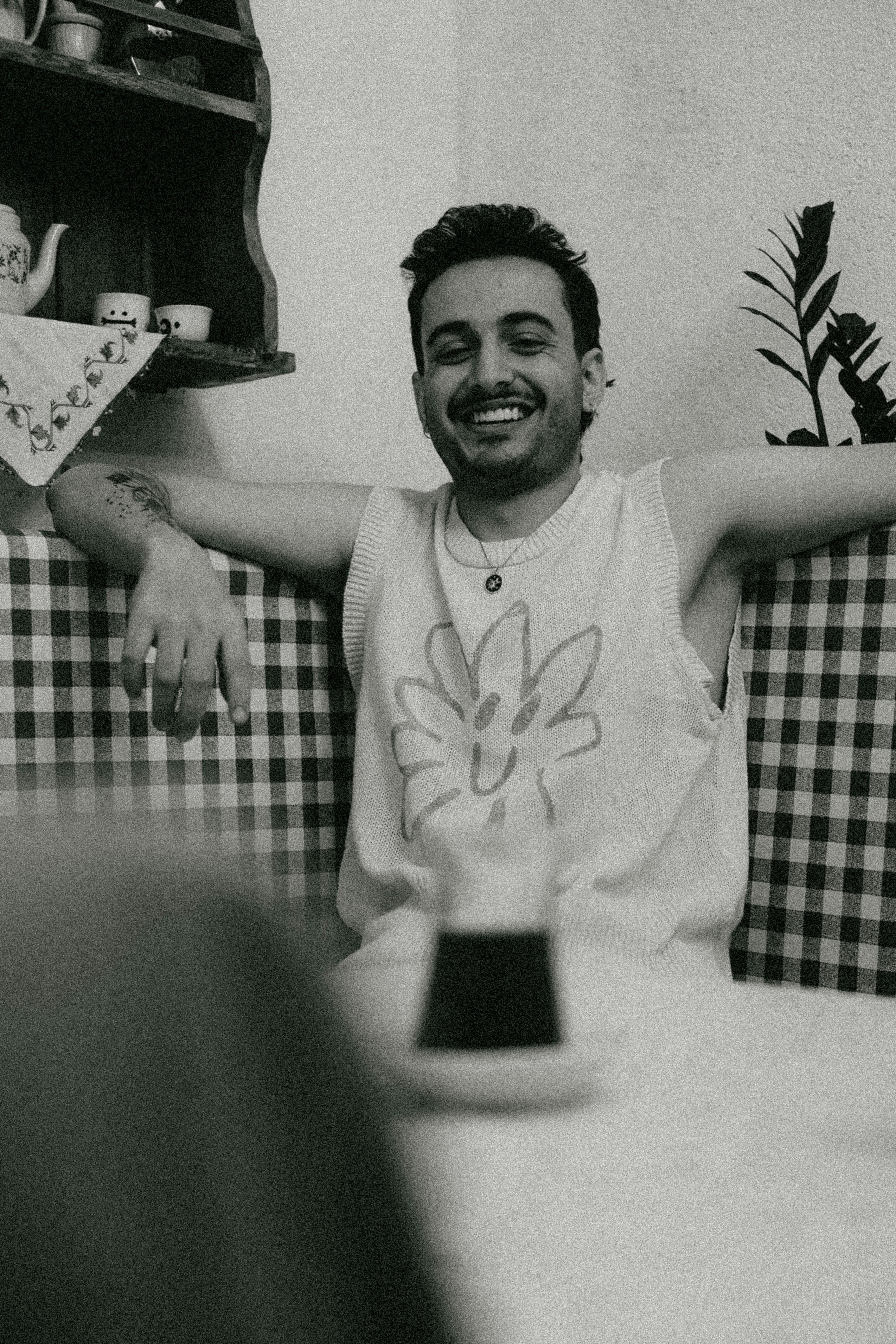 A joyful man in a checkered setting enjoys a relaxed moment indoors.
