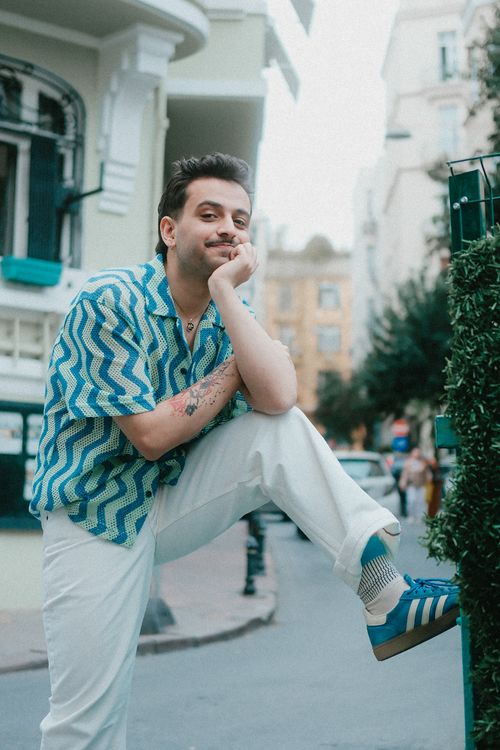 Free Casually dressed man in zigzag shirt poses confidently on a city street corner, showcasing summer style. Stock Photo