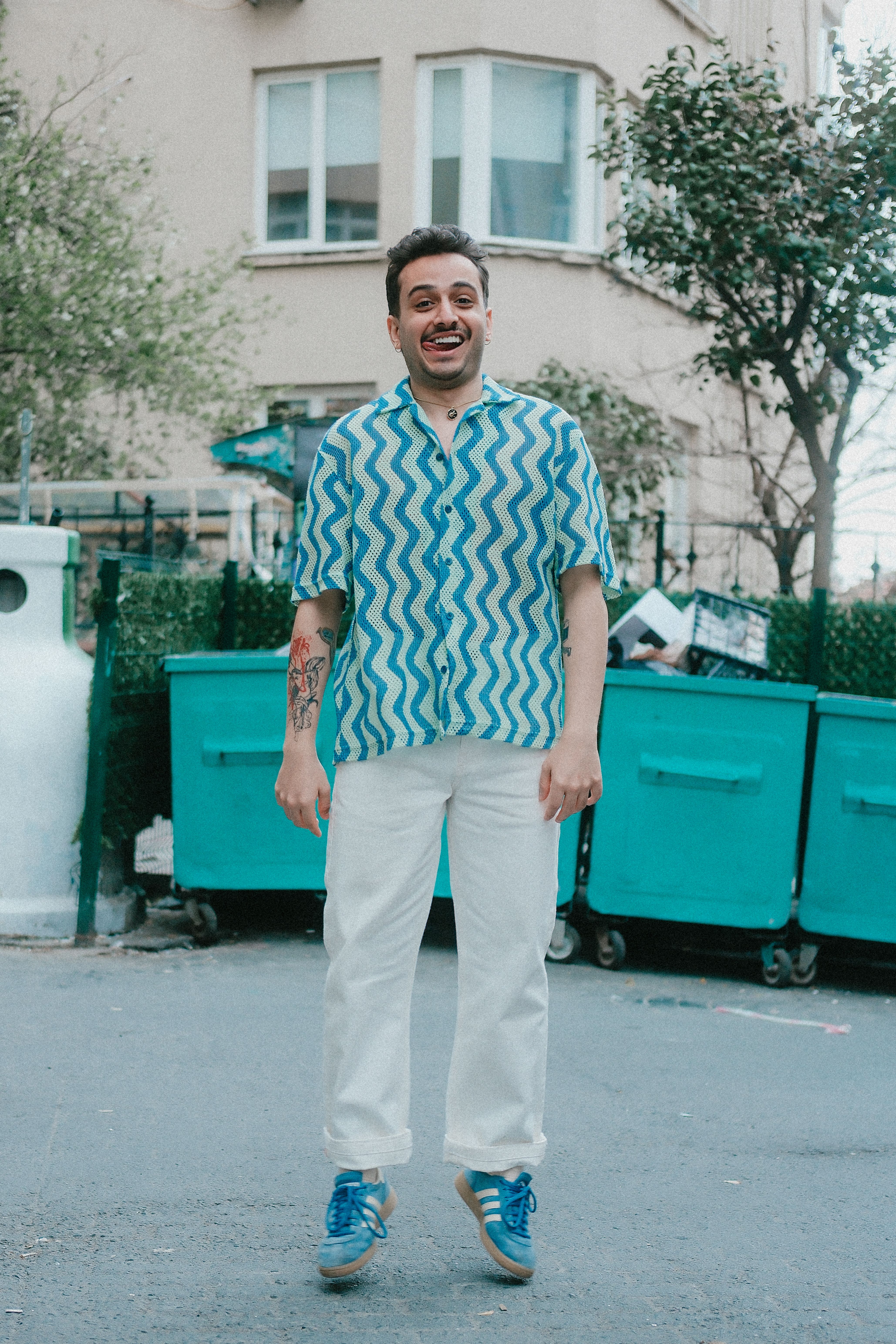 Cheerful man jumping in a casual outfit with vibrant shirt.