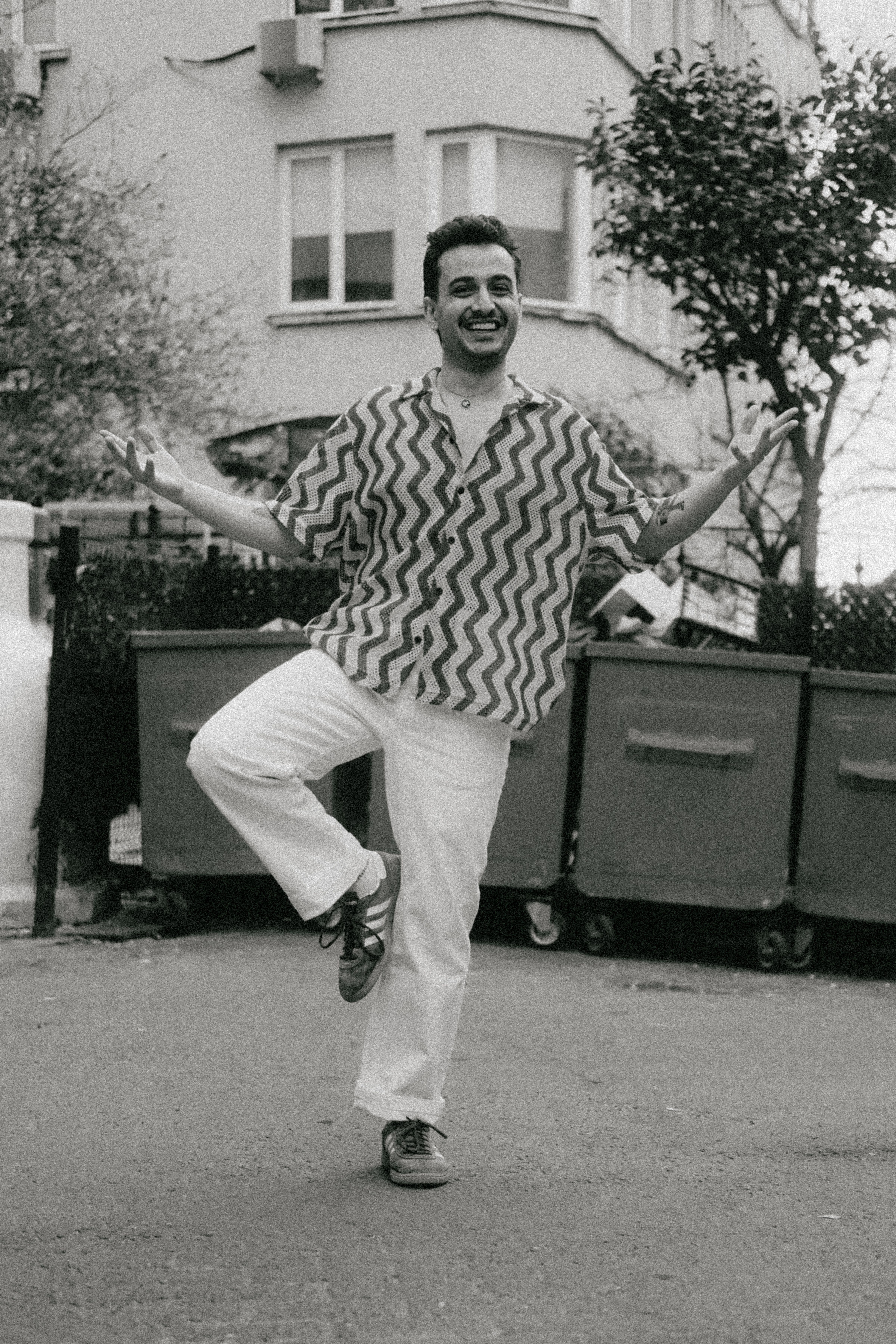 Black and white photo of a cheerful man dancing on a street in Istanbul, Türkiye.