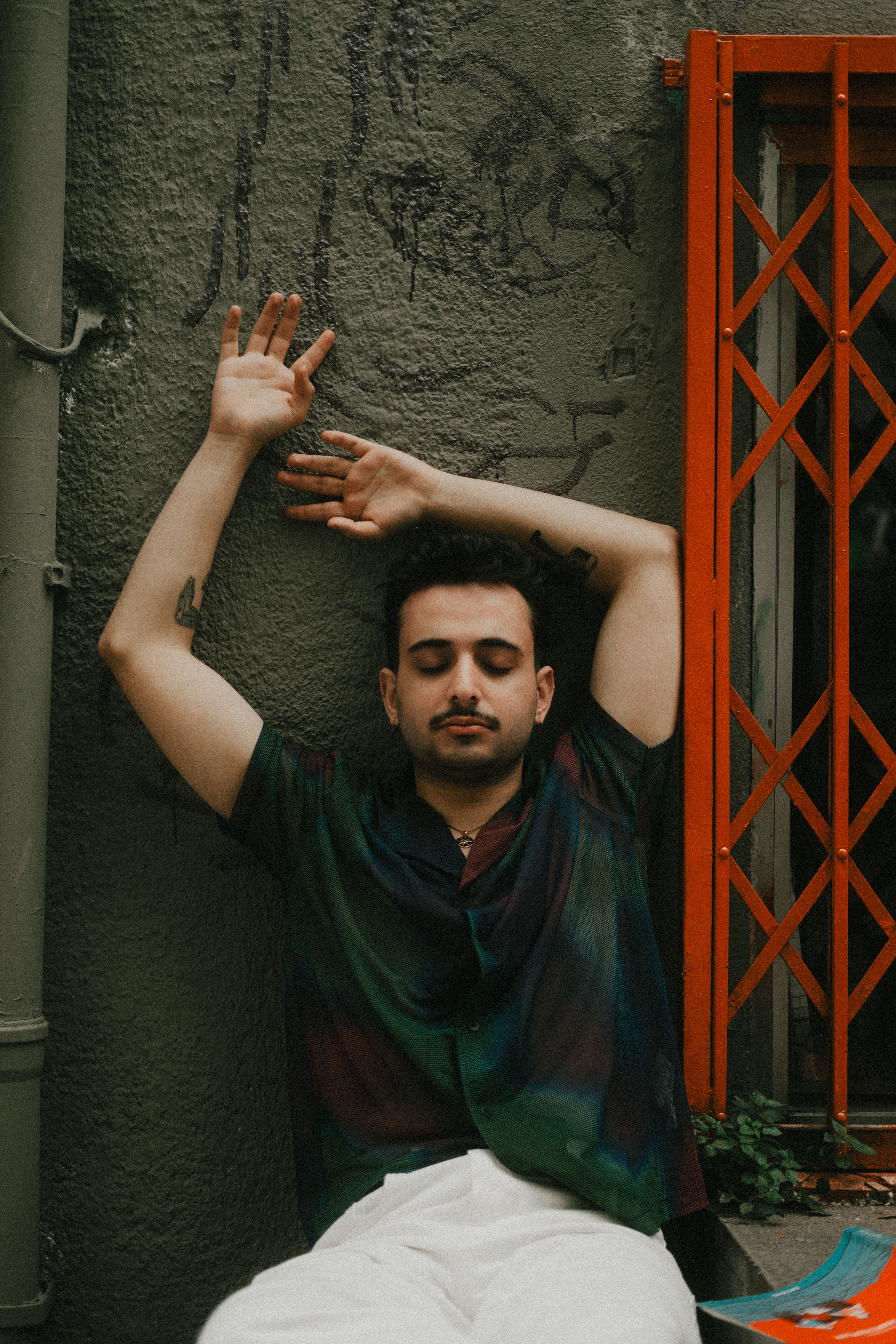 Young man in calm repose against textured urban wall, radiating peaceful vibes.
