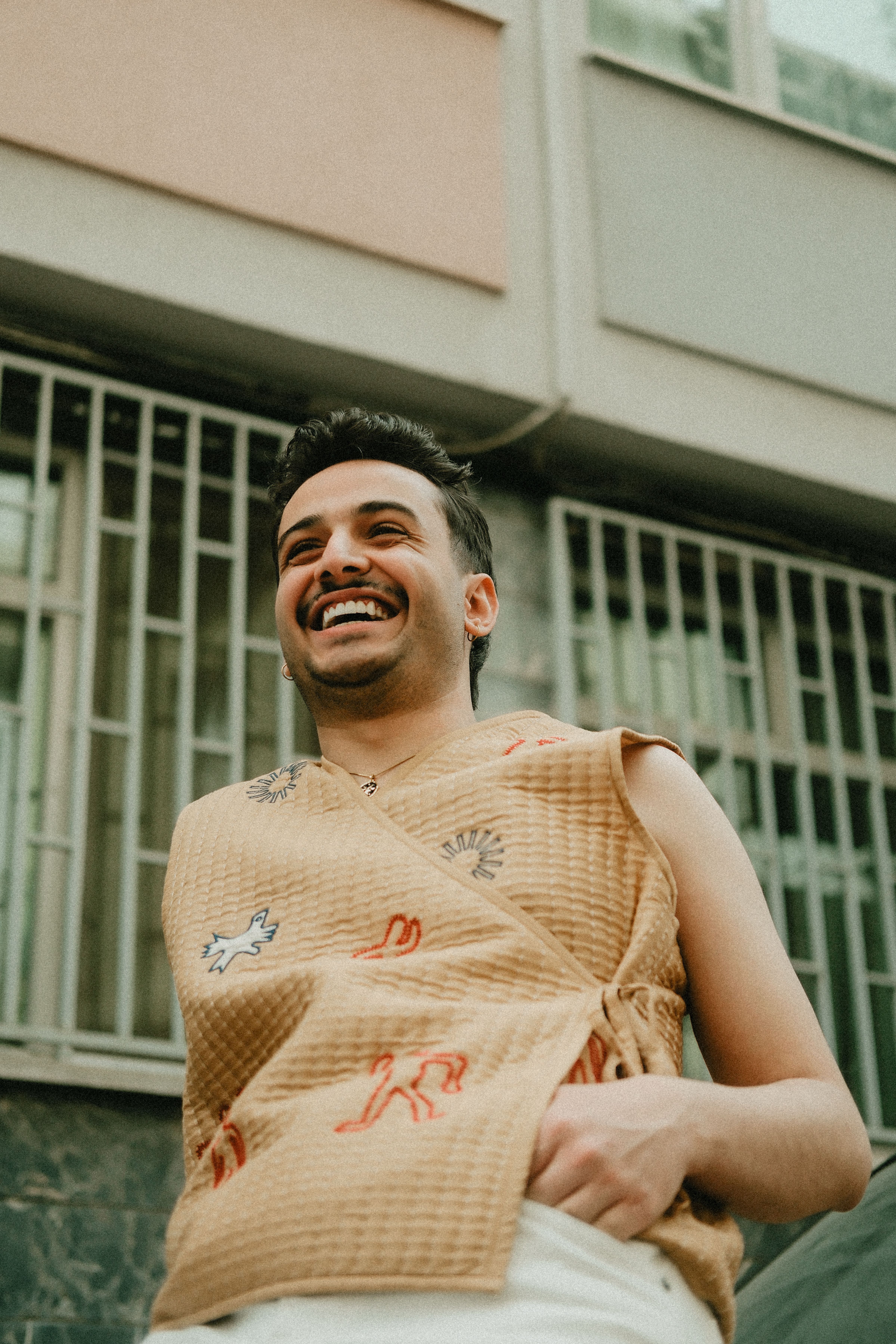 A cheerful man enjoys a moment outside in stylish clothing.