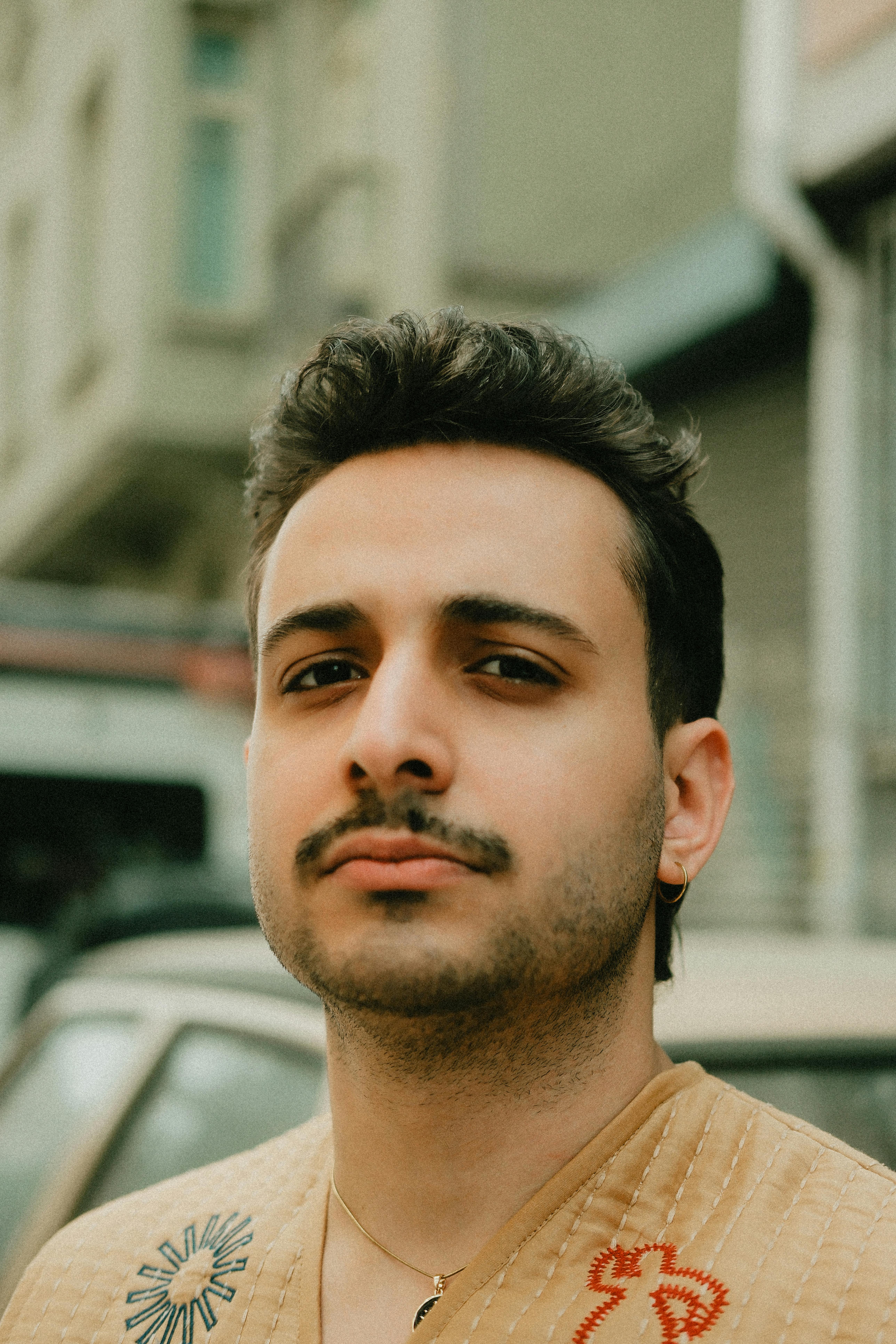 Portrait of a confident young man with urban buildings in the background.