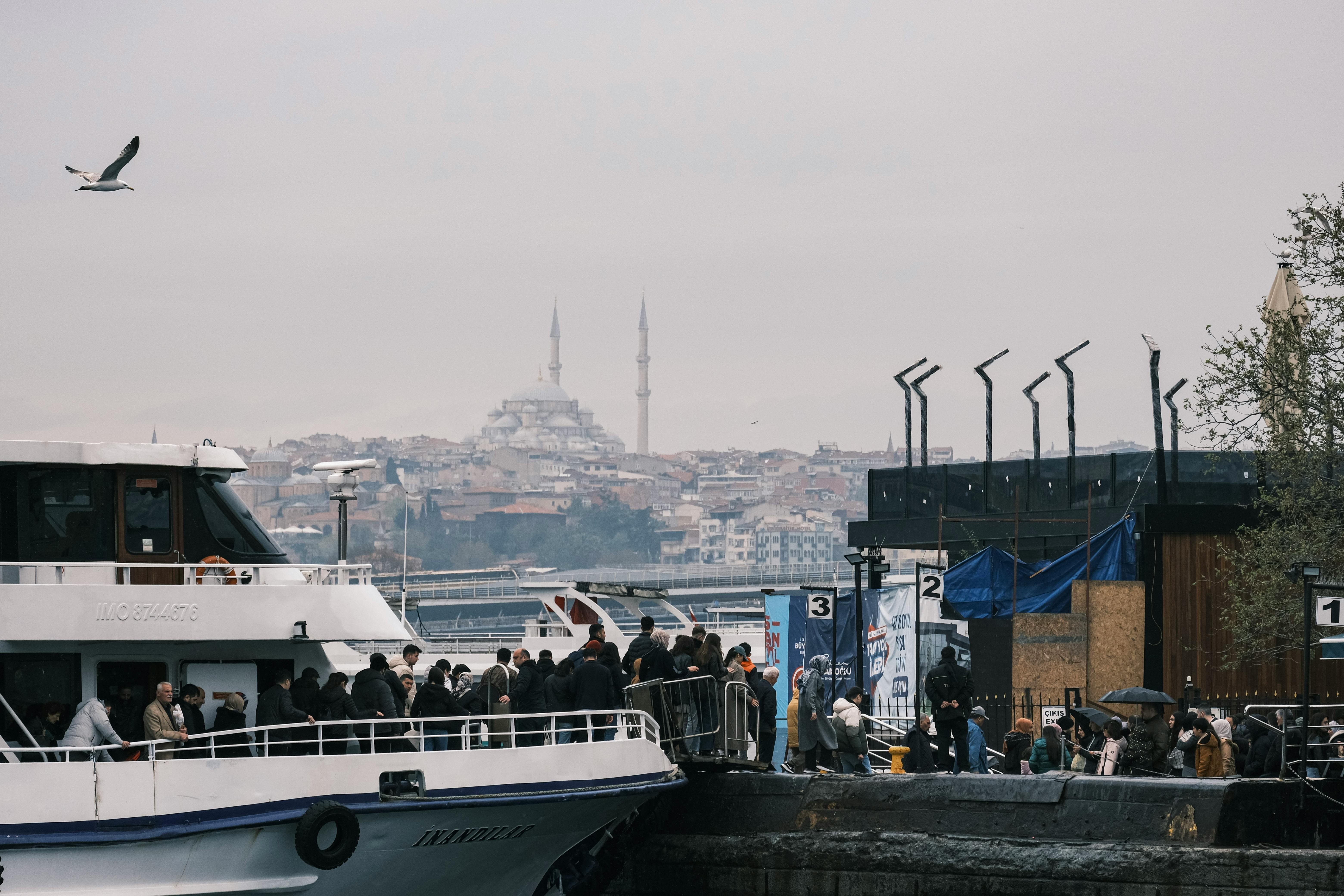 Gratuit Une scène portuaire animée à Istanbul avec des foules et une mosquée en arrière-plan. Photos