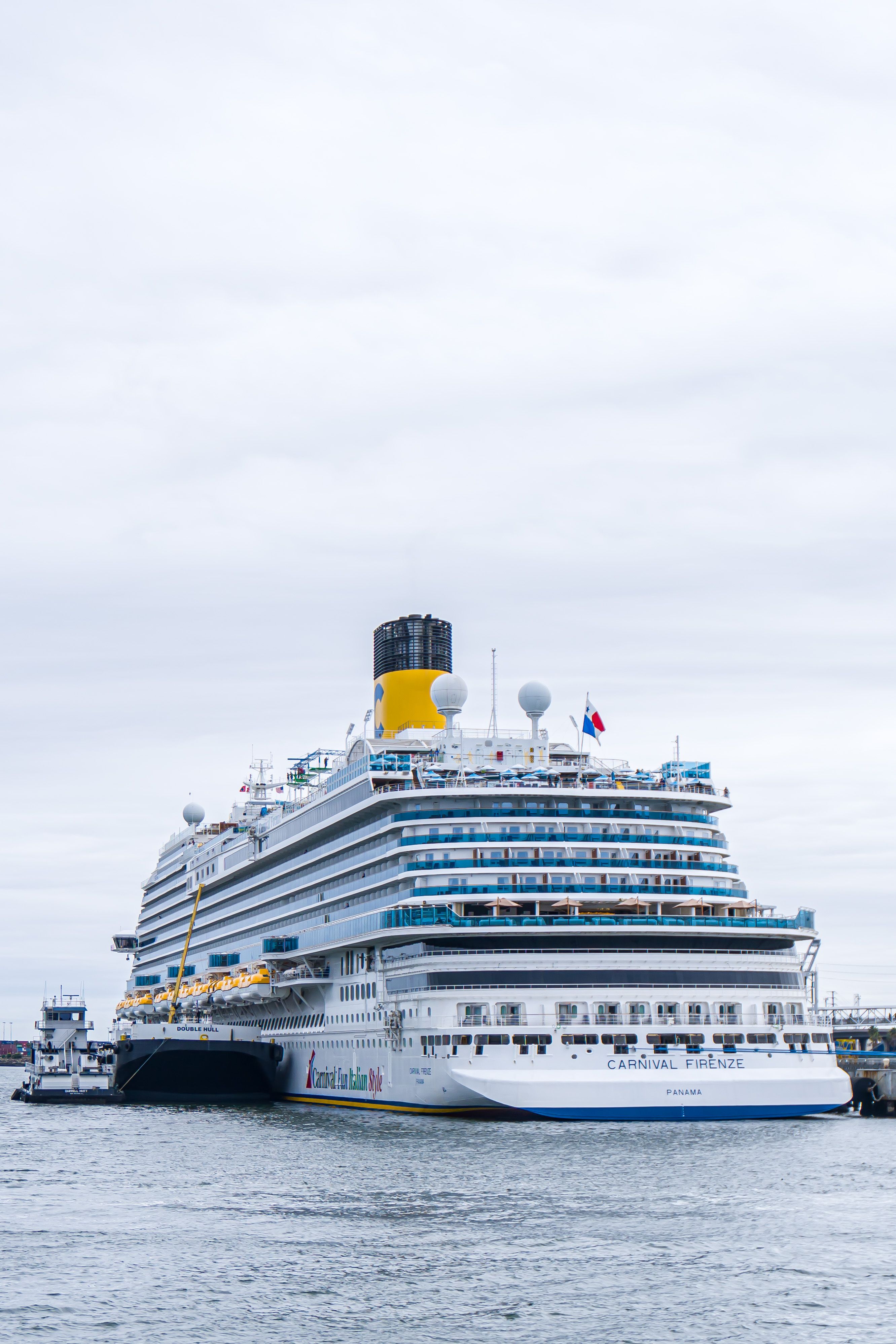 A massive cruise ship docked at the harbor under a cloudy sky, showcasing modern travel.