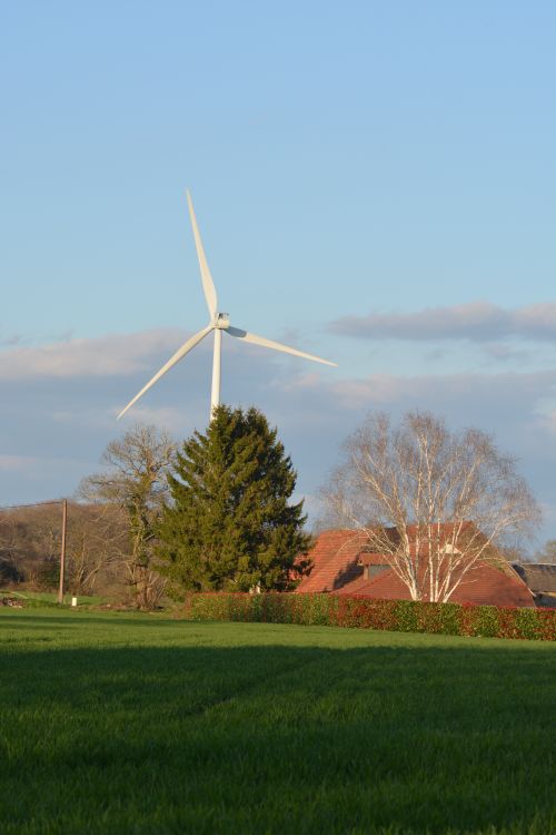 Free A wind turbine towers above a lush landscape in Creuse, Hauts-de-France. Stock Photo