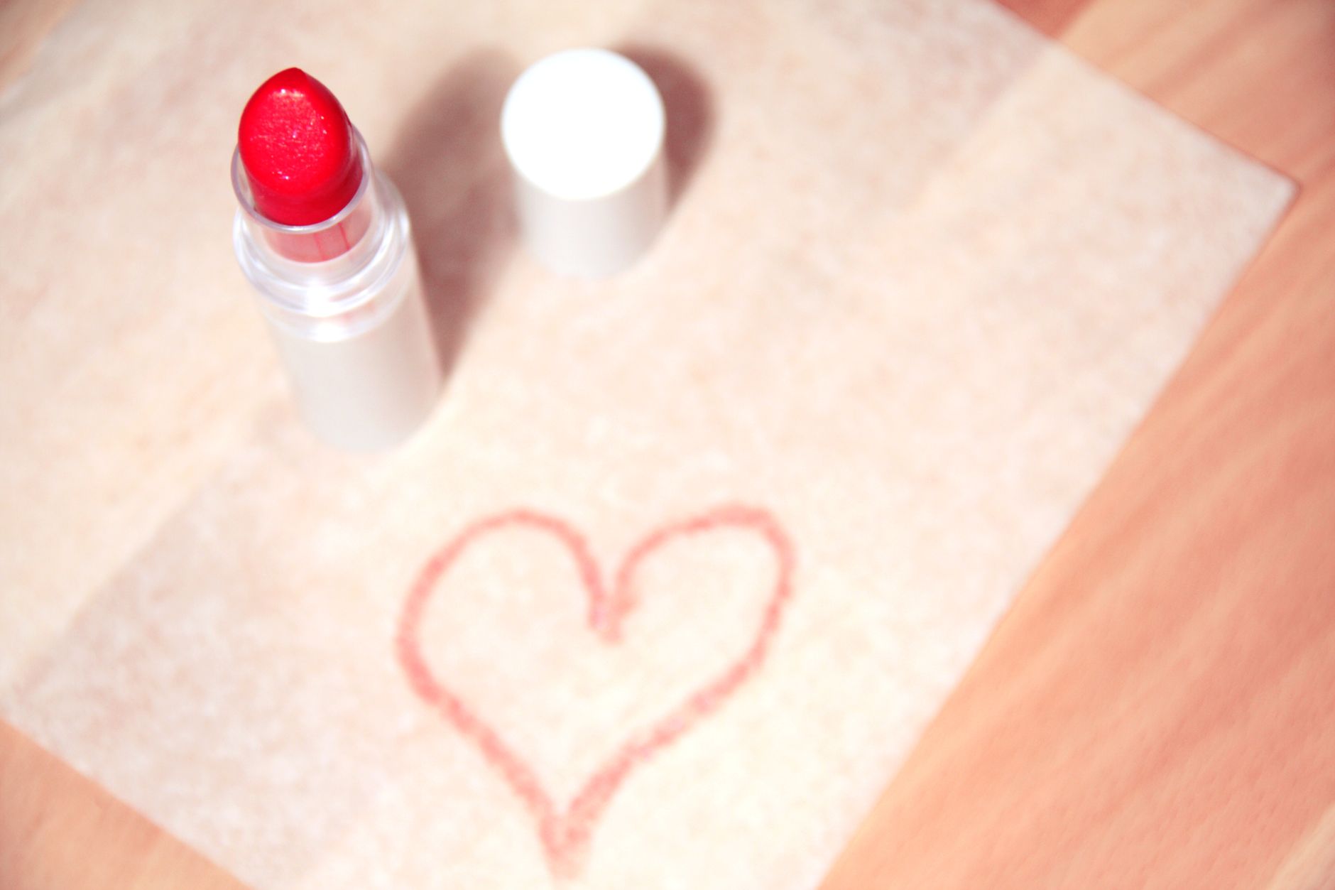Red lipstick with heart drawing on paper, representing love and beauty.