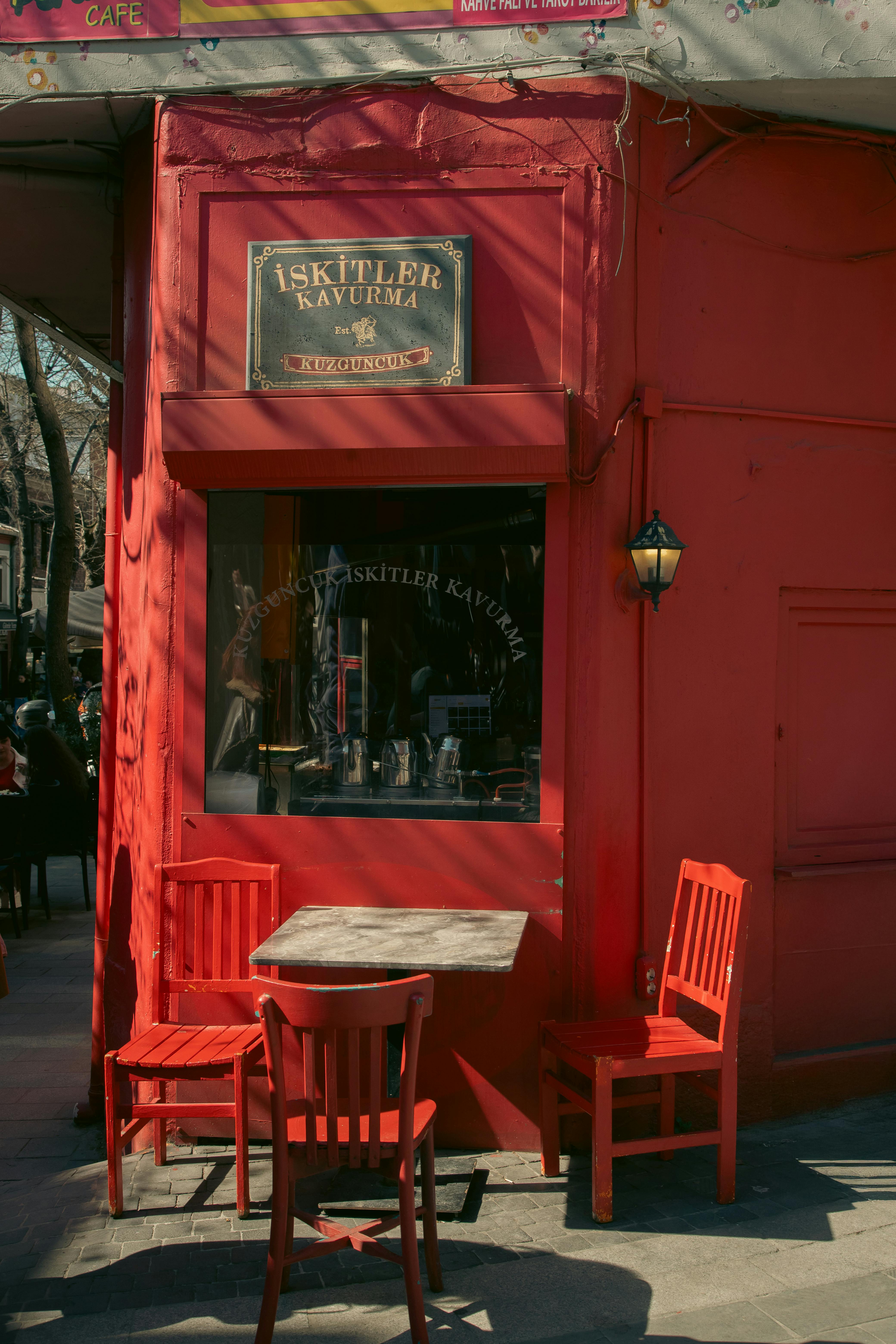 A vibrant red street cafe in Kuzguncuk, Istanbul, with outdoor tables and chairs.