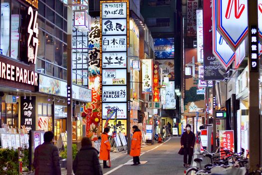 Explore the lively streets of Tokyo at night, illuminated by colorful signage and busy pedestrians.