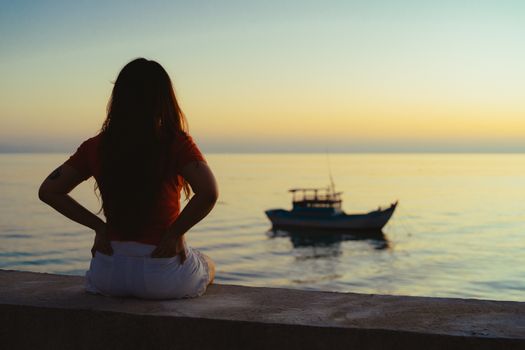 A serene scene of a person watching sunset over the ocean with a distant boat in Bình Thuận, Vietnam.