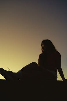 A silhouette of a woman sitting at sunset, captured in Bình Thuận, Vietnam.