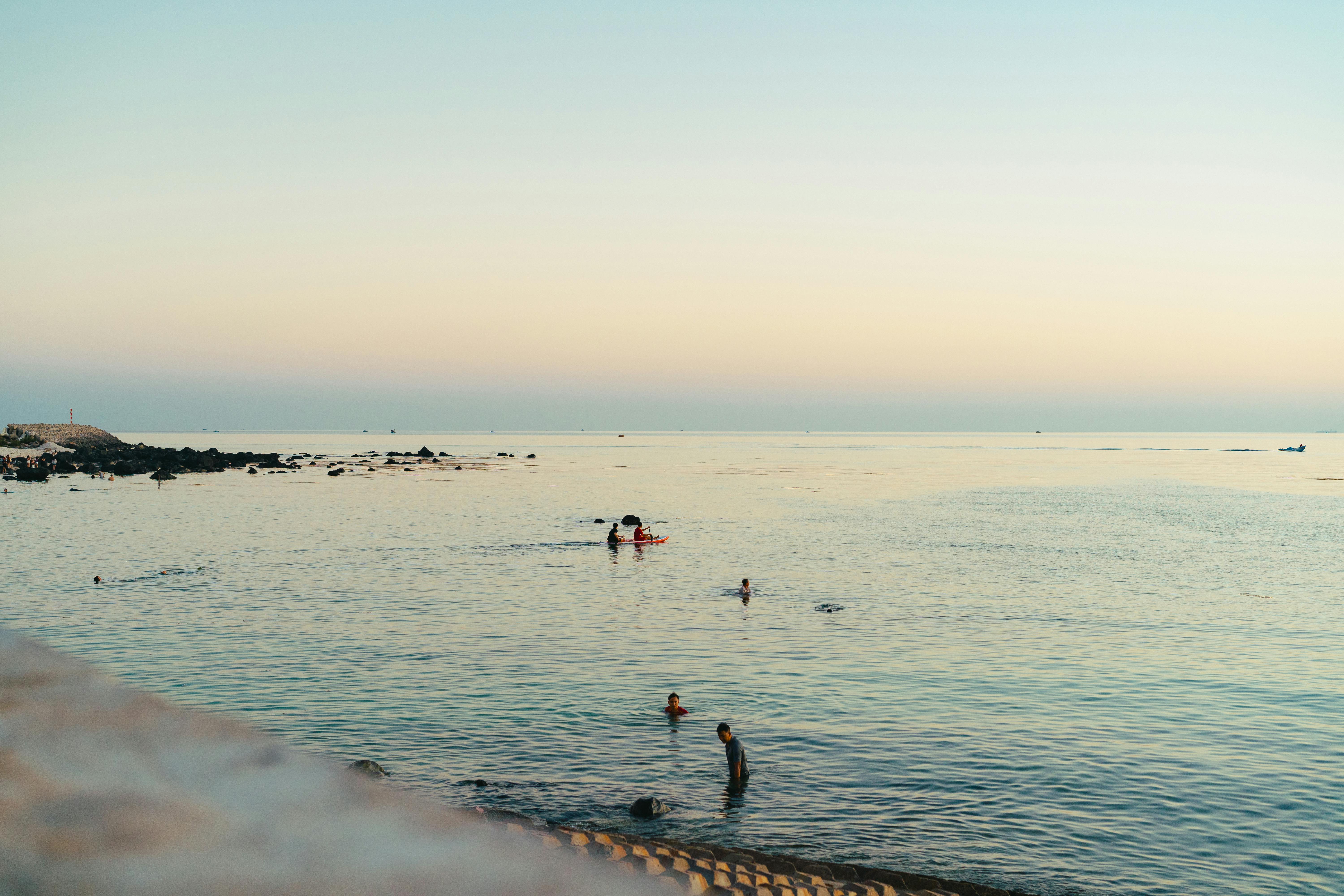 Peaceful beach scene at sunset in Bình Thuận, Vietnam, with swimmers enjoying the calm sea.
