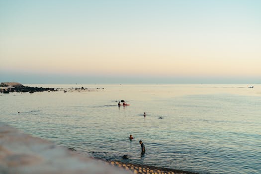 Peaceful beach scene at sunset in Bình Thuận, Vietnam, with swimmers enjoying the calm sea.