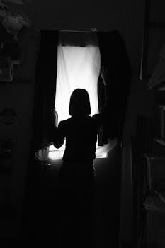黑暗中，窗前一个人的轮廓，在单色环境里显得神秘而迷人