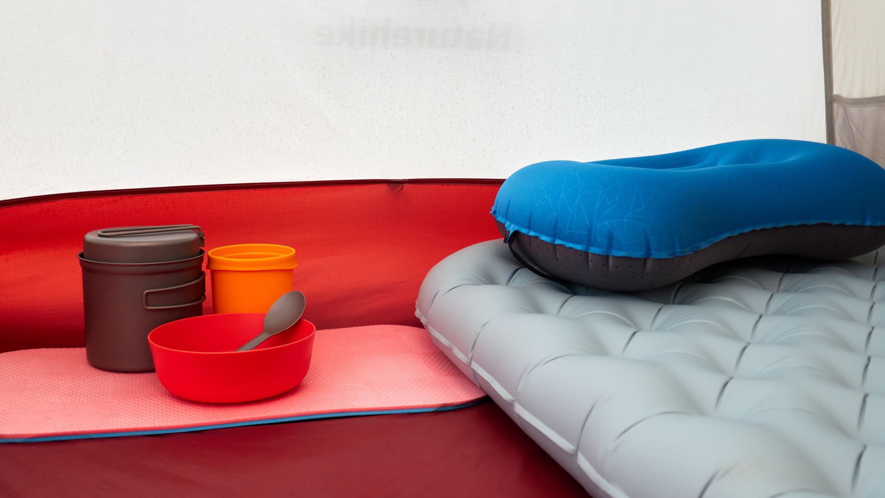 Sleeping pad and inflatable camping pillow arranged inside a tent