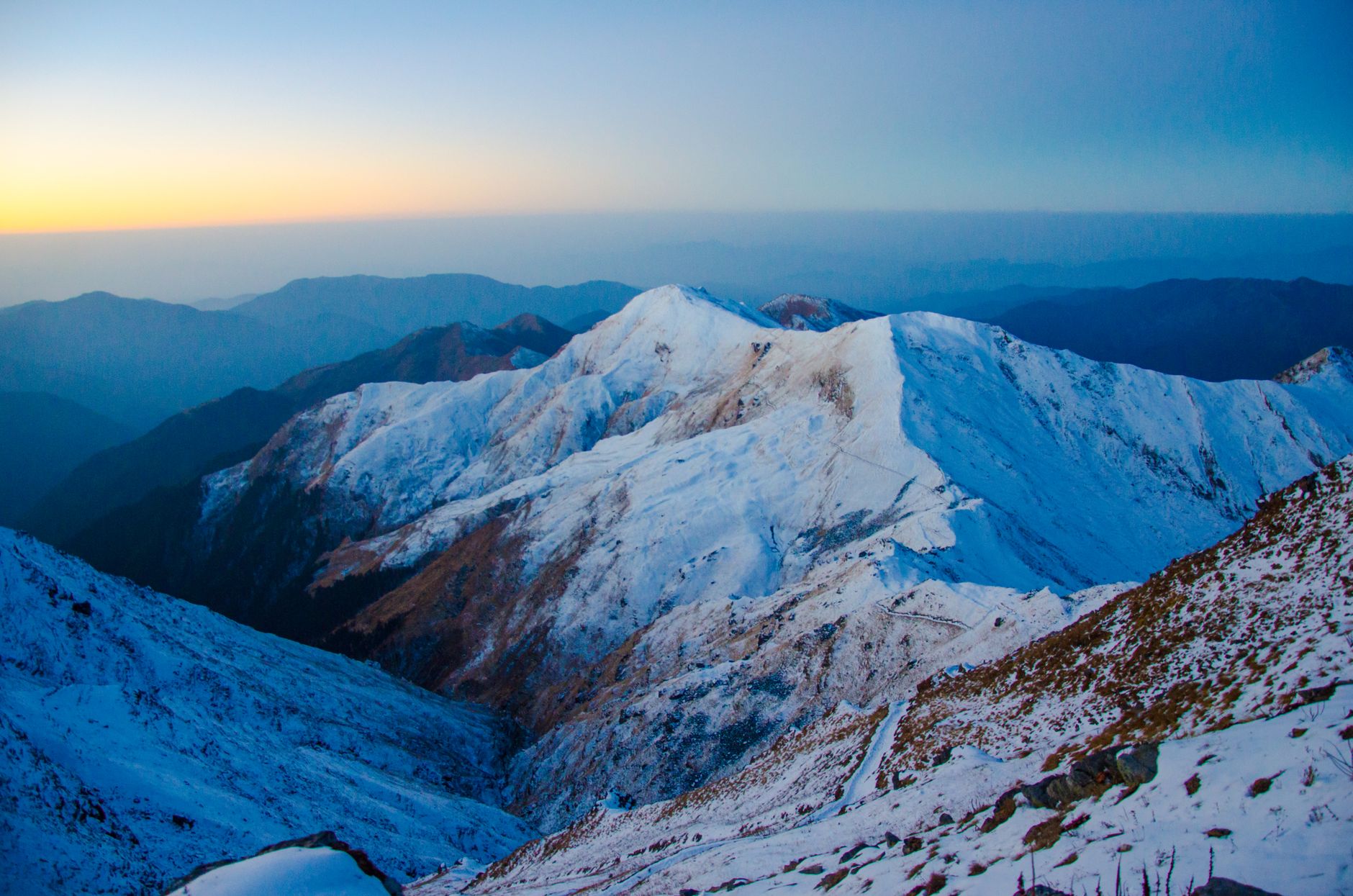 Stunning snow-covered peaks at sunrise in Uttarakhand, showcasing serene mountain beauty.