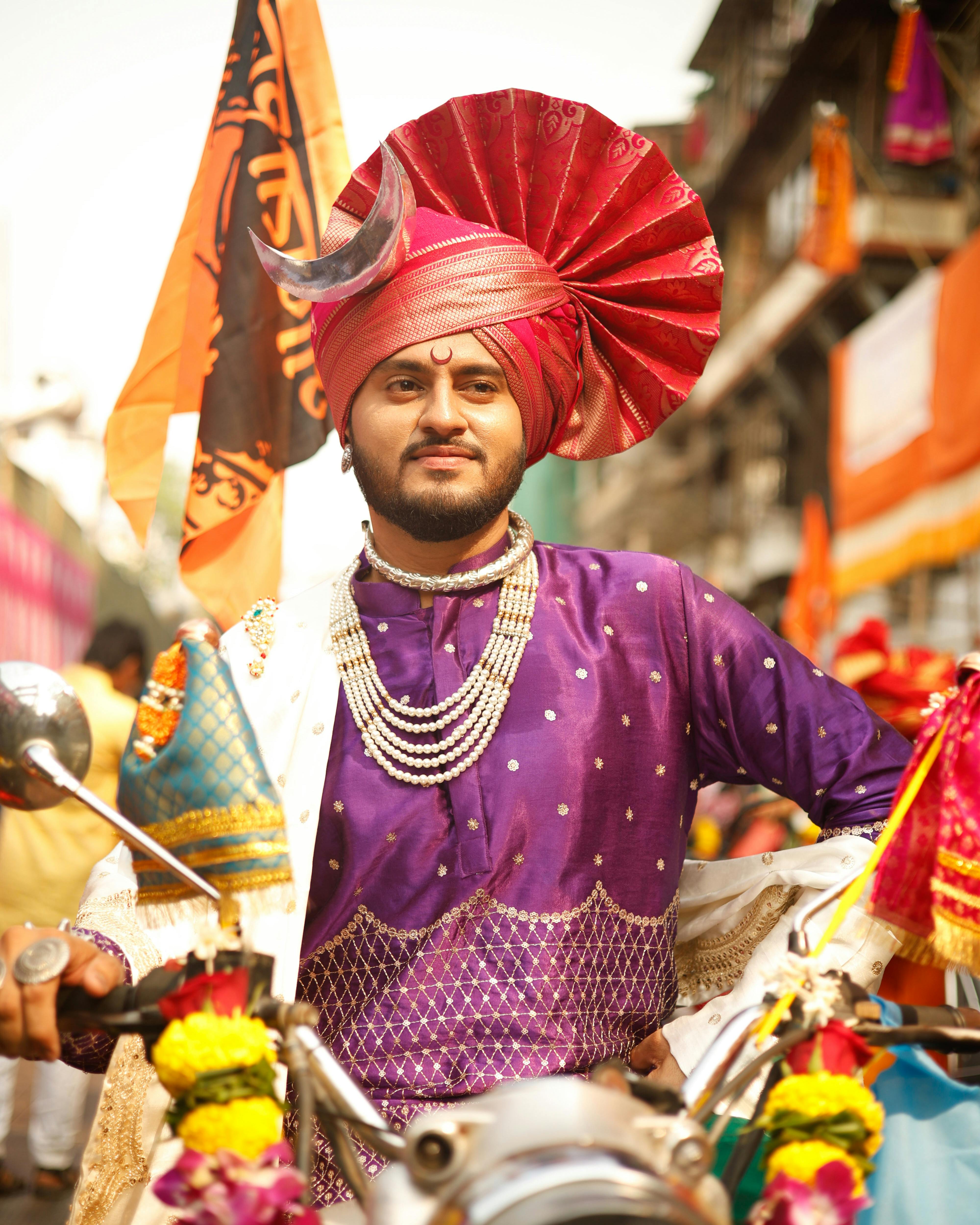 Man in vibrant traditional Indian attire posing during a cultural festival street parade.