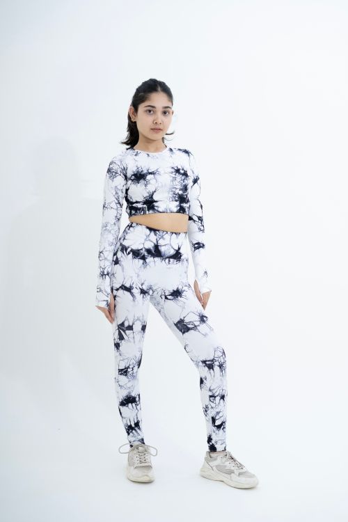 Free Young woman in trendy tie-dye activewear posing confidently indoors. Stock Photo