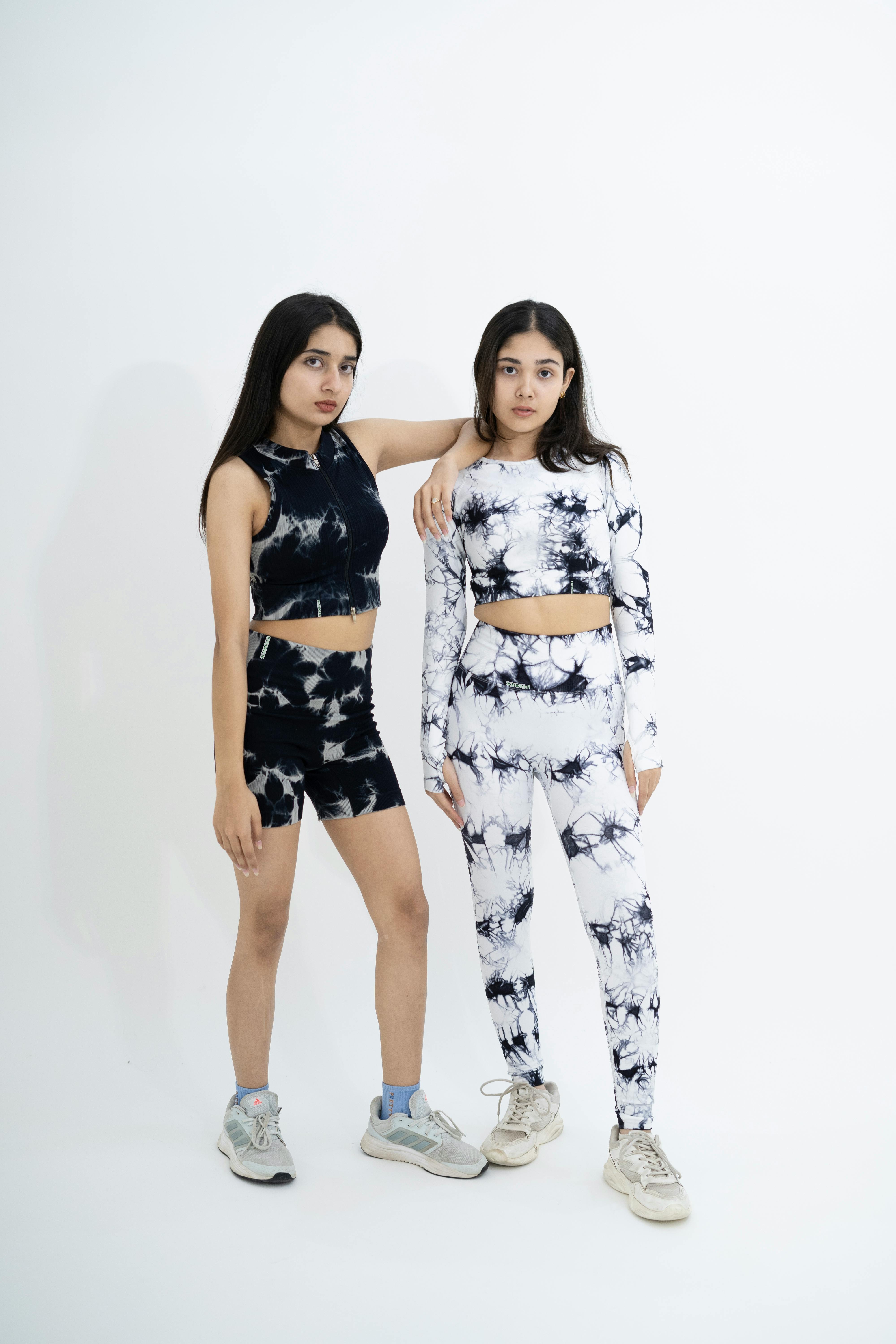 bezplatná Dvě mladé ženy pózují ve stylovém černém a bílém kravatovém aktivním oblečení uvnitř. Základová fotografie