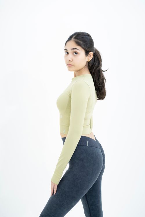 Free Confident young woman in trendy fitness outfit posing in minimalistic studio setting. Stock Photo