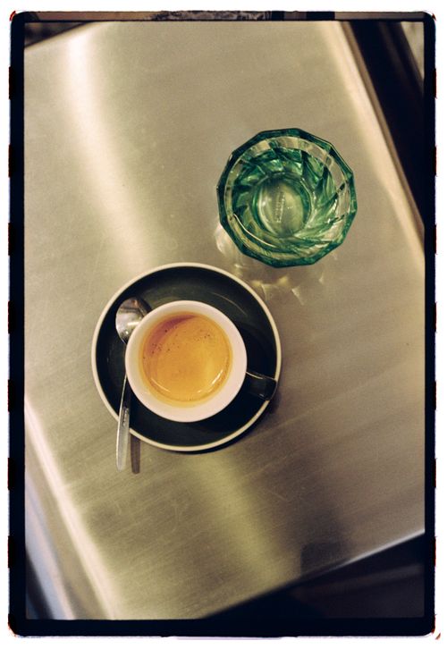 Free Top view of espresso cup and green glass on metallic table, simple composition. Stock Photo