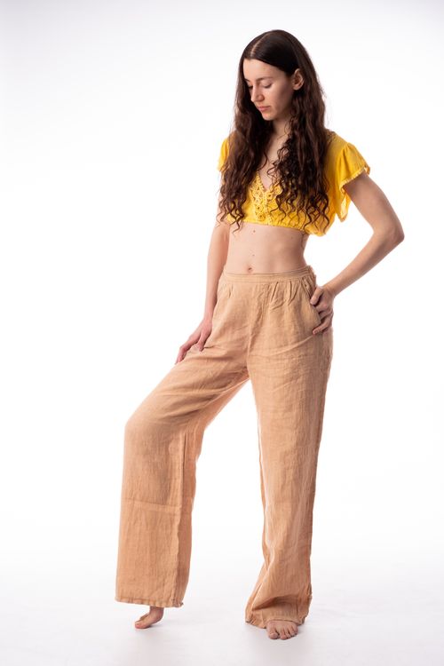 Free Studio shot of a woman in a stylish yellow top and beige pants, posing against a white background. Stock Photo