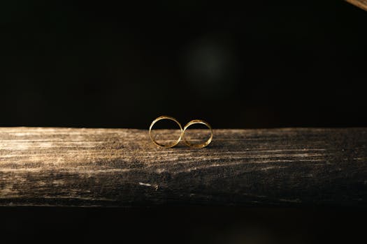 Close-up of two gold wedding rings on rustic wood against a dark background.