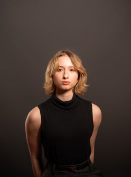 Studio portrait of a young woman in a black outfit with a neutral background.