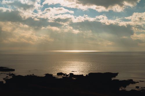 Free Serene view of Bình Thuận's coastline at sunset with dramatic clouds and shimmering waters. Stock Photo
