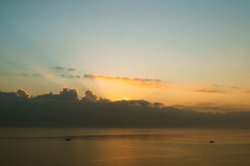 Free A serene sunset over the calm ocean with boats in Bình Thuận, Vietnam. Stock Photo