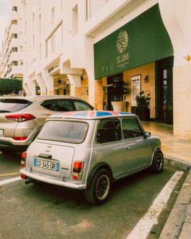 A classic Mini Cooper parked on a vibrant Rabat street with retro charm and urban vibes.