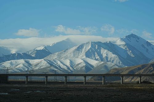 Free A striking view of snow-covered mountains with a highway bridge in the foreground under a clear blue sky. Stock Photo