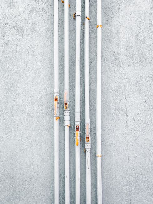 A minimalist view of industrial pipes aligned against a concrete wall in India, showcasing urban design. A minimalist view of industrial pipes aligned against a concrete wall in India, showcasing urban design.