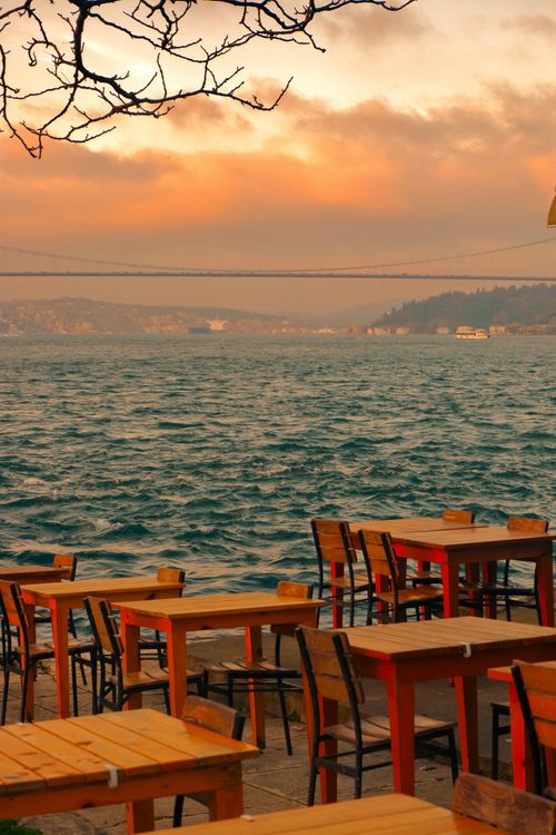 Free Outdoor café with wooden tables by the sea during a beautiful sunset. Stock Photo